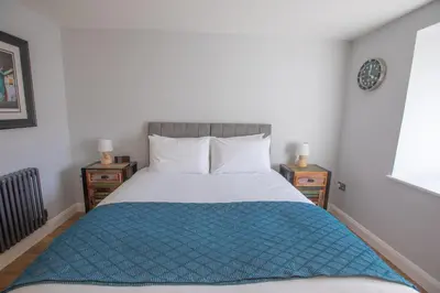 a bedroom with a large bed with a blue blanket at UPPER BEACH HOUSE in Portreath