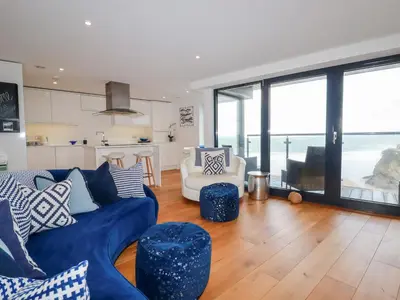 a living room with a blue couch and a kitchen at Towan Penthouse in Newquay