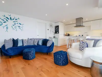 a living room with blue couches and a kitchen at Towan Penthouse in Newquay