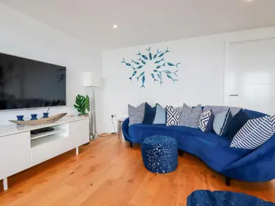 a living room with a blue couch and a tv at Towan Penthouse in Newquay