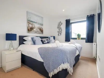 a bedroom with a large bed with blue curtains at Towan Penthouse in Newquay