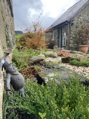 a garden with a statue in front of a building at The Artists Barn in Launceston