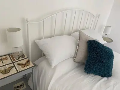 a white bed with white pillows and a blue pillow on it at The Artists Barn in Launceston