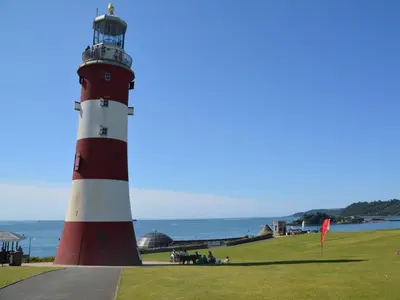 a red and white lighthouse sitting next to the ocean at 2 Bed in Callington oc-kates in North Hill