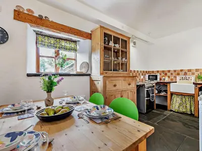 a kitchen with a wooden table and green chairs at 2 Bed in Launceston oc-02038 in North Petherwin