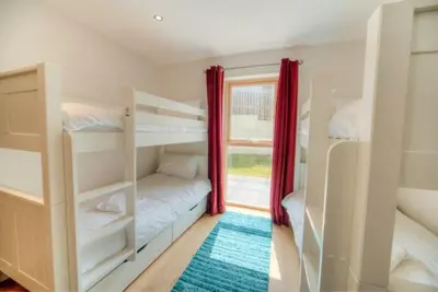 a room with two bunk beds and a window at House 12 in Looe