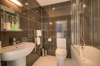a bathroom with a sink and a toilet and a tub at House 12 in Looe