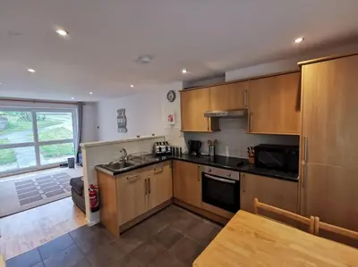 a kitchen with wooden cabinets and a table in it at Cornwall Holiday Home, Casa Da Praia in Saint Columb Major