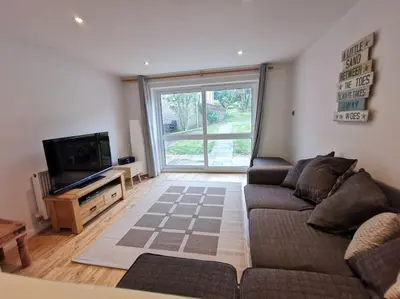 a living room with a couch and a television at Cornwall Holiday Home, Casa Da Praia in Saint Columb Major