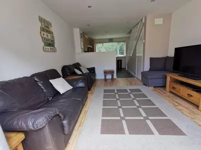 a living room with a leather couch and a flat screen tv at Cornwall Holiday Home, Casa Da Praia in Saint Columb Major