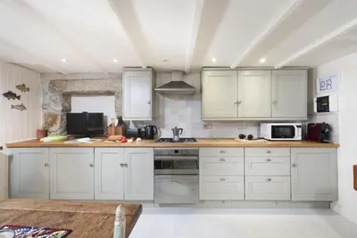 a kitchen with white cabinets and white appliances at Tathra Beach Cottage in St Ives