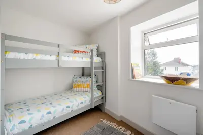 a white room with a bunk bed and a window at Cosy cottage near the coast in Tywardreath