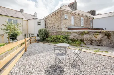 a patio with a table and chairs in front of a building at Cosy cottage near the coast in Tywardreath