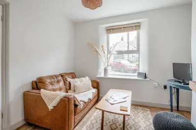 a living room with a brown leather couch and a table at Cosy cottage near the coast in Tywardreath