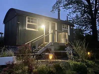 a tiny house with the lights on in a garden at 1 Bedroom Cabin Sleeps 2 Private Garden WiFi in Camelford