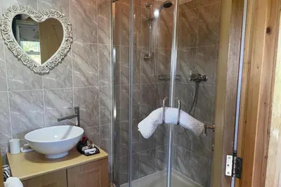 a bathroom with a shower with a sink and a mirror at 1 Bedroom Cabin Sleeps 2 Private Garden WiFi in Camelford