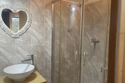 a bathroom with a shower with a sink and a mirror at 1 Bedroom Cabin Sleeps 2 Private Garden WiFi in Camelford