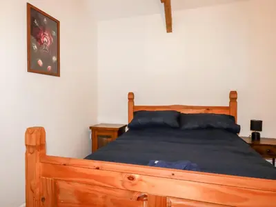 a bedroom with a wooden bed with blue sheets at The Old Cattle Barn in Launceston
