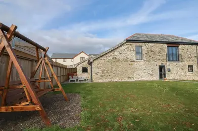 a stone house with a yard with a swing at The Old Cattle Barn in Launceston