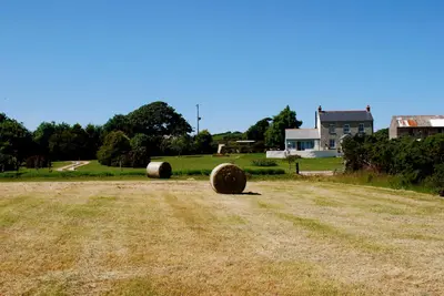 two hay bales in a field in front of a house at Fig Tree House in Penryn