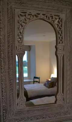 a mirror reflecting a bed in a bedroom at Fig Tree House in Penryn