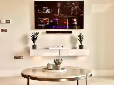 a living room with a table and a tv on the wall at Quiet Clifftop luxury apartment with partial seaviews in Newquay