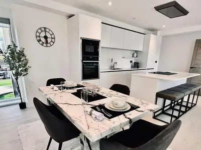 a kitchen and dining room with a marble table and chairs at Quiet Clifftop luxury apartment with partial seaviews in Newquay