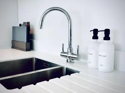 a kitchen with a sink and two bottles of soap at Quiet Clifftop luxury apartment with partial seaviews in Newquay