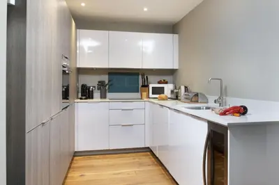 a kitchen with white cabinets and a wooden floor at Rockpool at Salt in St Ives