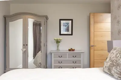 a bedroom with a bed and a dresser with a mirror at Rockpool at Salt in St Ives