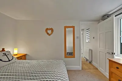 a bedroom with a bed and a mirror on the wall at Finest Retreats - Porthole Cottage in Mevagissey