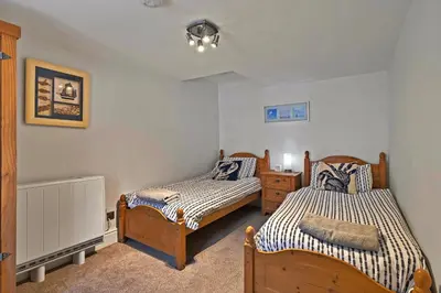 a bedroom with two beds and a dresser at Finest Retreats - Porthole Cottage in Mevagissey