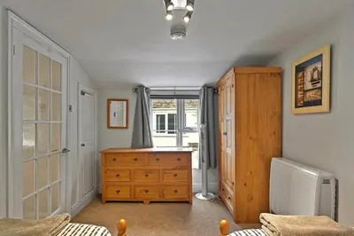 a bedroom with a wooden dresser and a window at Finest Retreats - Porthole Cottage in Mevagissey