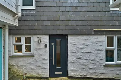 a house with a blue door and two windows at Finest Retreats - Porthole Cottage in Mevagissey