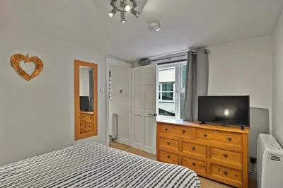 a bedroom with a bed and a television on a dresser at Finest Retreats - Porthole Cottage in Mevagissey