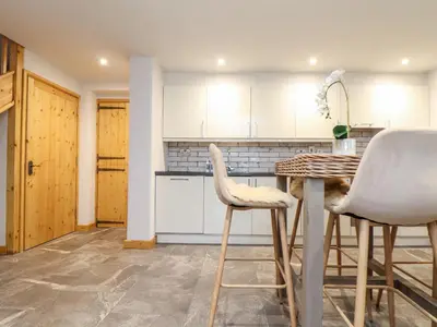 a kitchen with white cabinets and a table and chairs at La Petit Maison in Saint Columb Major