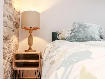 a bedroom with a bed and a lamp on a night stand at La Petit Maison in Saint Columb Major