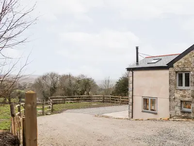 a house on a dirt road next to a fence at La Petit Maison in Saint Columb Major
