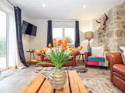 a living room with a vase of flowers on a table at La Petit Maison in Saint Columb Major