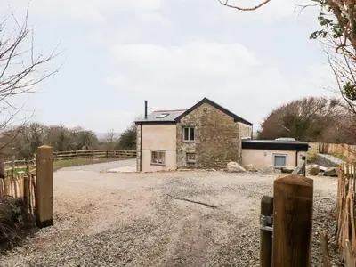 a house on a dirt road next to a fence at La Petit Maison in Saint Columb Major