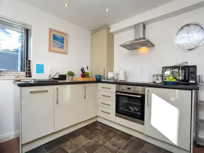 a kitchen with white cabinets and a stove at The Lodge in Carlyon Bay