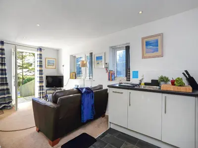 a living room with a couch and a kitchen at The Lodge in Carlyon Bay