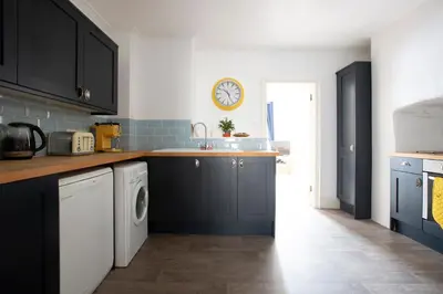 a kitchen with black cabinets and a clock on the wall at Elegant 2 bed in the heart of Falmouth - sleeps 4 in Falmouth