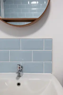 a bathroom with blue tiles and a sink with a mirror at Elegant 2 bed in the heart of Falmouth - sleeps 4 in Falmouth