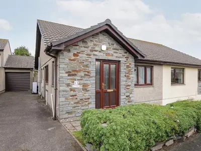 a small brick house with a red door at St Albans in Boscastle