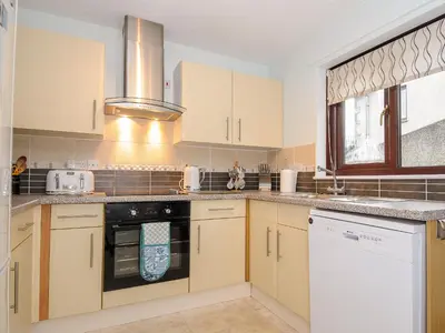 a kitchen with white cabinets and a stove top oven at St Albans in Boscastle