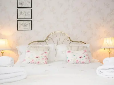 a bedroom with a white bed with pink wallpaper at St Albans in Boscastle