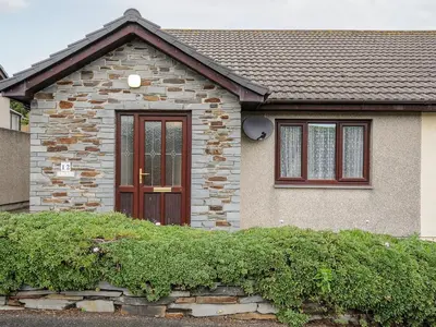 a brick house with a brown door and windows at St Albans in Boscastle