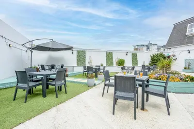 a patio with tables and chairs and an umbrella at Barrowfield Hotel in Newquay