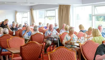 a group of people sitting at tables in a restaurant at Barrowfield Hotel in Newquay